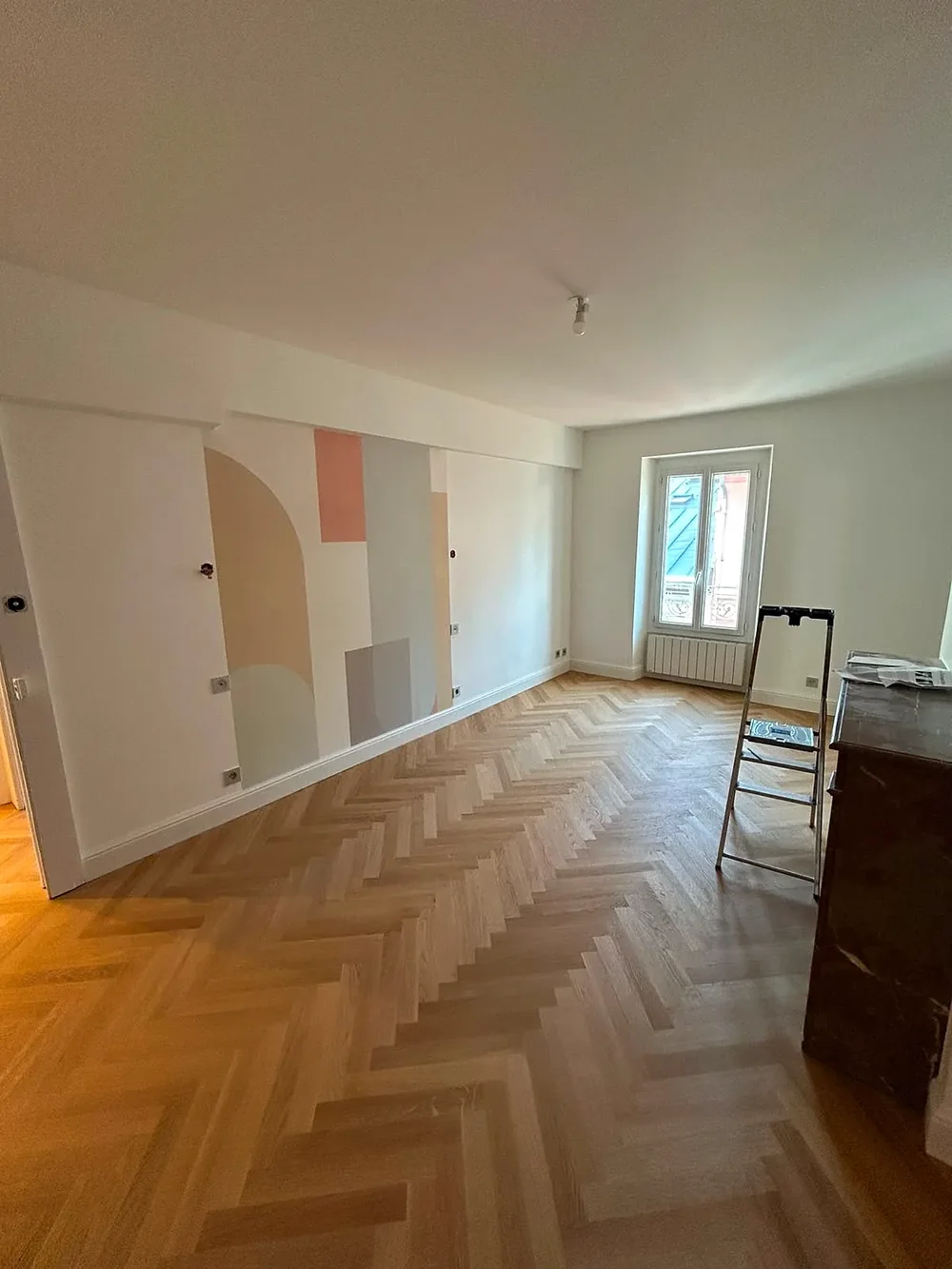 Salon rénové avec parquet point de Hongrie et fresque géométrique pastel, chantier ROD Peinture
